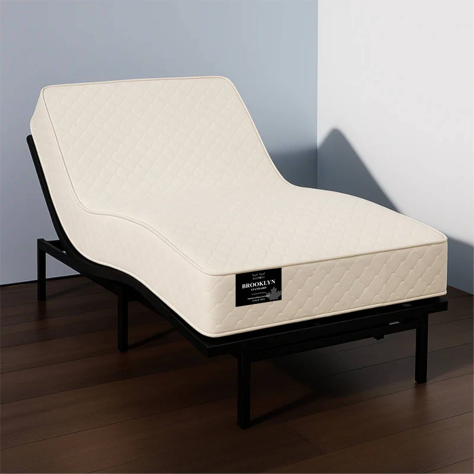 "Brooklyn Standard mattress on an adjustable bed base shown from a front angle in a studio bedroom setting — Sleepwell Bedding."