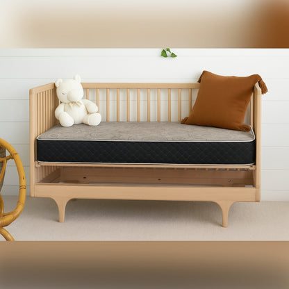 Crib mattress on natural wood toddler bed in cozy nursery