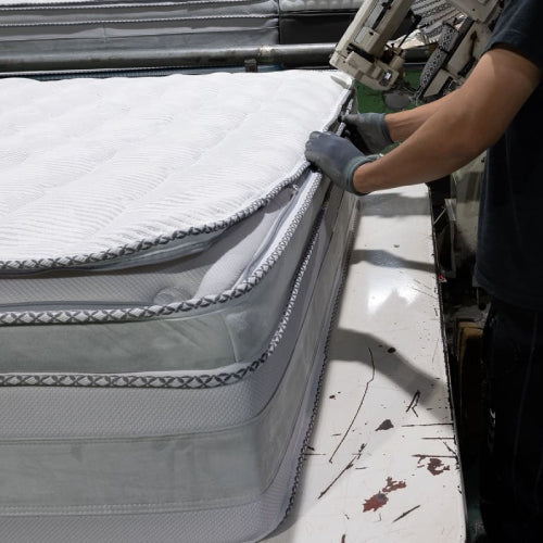 Close-up of SleepWell pillow-top mattress edge during manufacturing