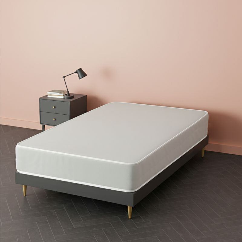 White mattress on a grey upholstered bed frame with wooden legs, in a pink bedroom setting – SleepWell